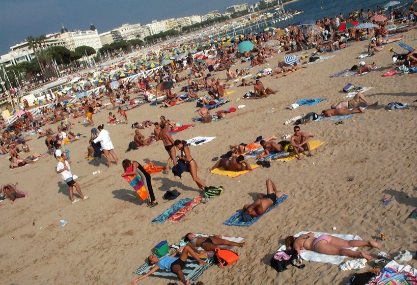 Sunbathers pack the beach on a sunny August afternoon.  Cannes, South of France.