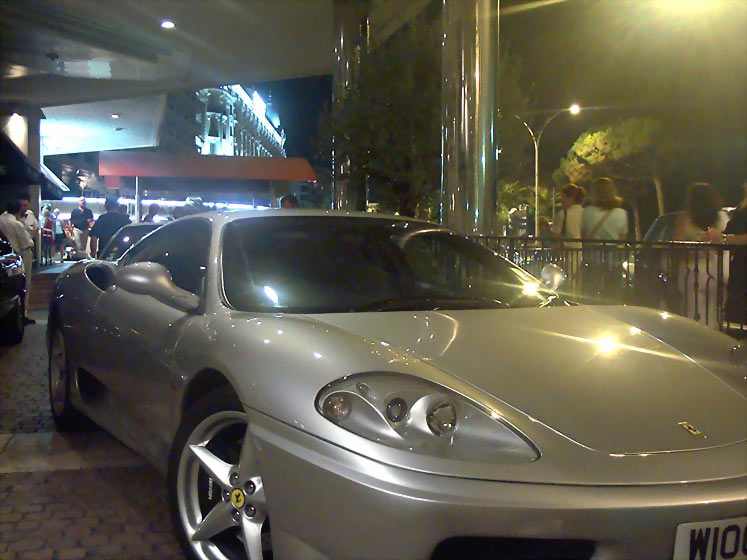 A new silver Ferrari sports car parked at the entrance to a luxury hotel at night.  Cannes, South of France.