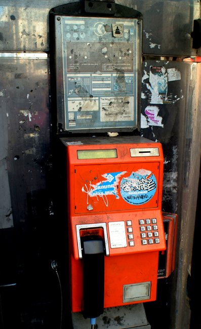 Sad to say a typical UK public phone, covered in the remnants of numerous sticker marketing campaigns, vandals and other undesirable clients.  London, U.K.