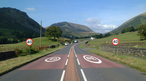 Typically English beautifully paved country road complete with clear road markings and signs cut through the picturesque rolling countryside.  Lake District, England, U.K.