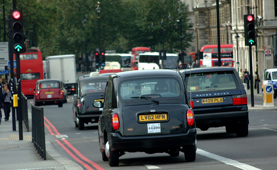 Various types of London Taxi Cabs and traditional red English double decker buses fill the on a busy streets.  London, U.K..