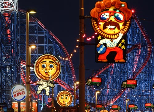 Bright lights from the annual street lighting festival in the northern English town of Blackpool crisscross in front of the Pepsi Max rollercoaster, one of the tallest fastest rollercoasters in the world.  Blackpool Pleasure Beach, Blackpool, U.K..