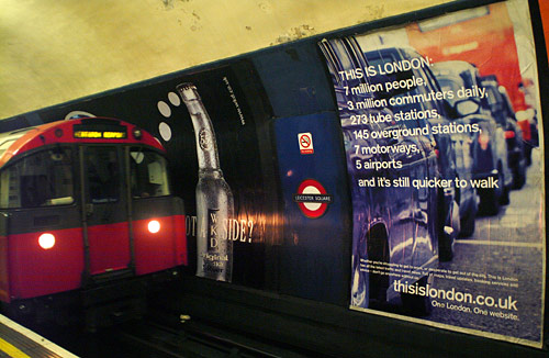 A very amusing advertising billboard highlights some of London's traffic problems as a train pulls into Leicester Square tube / subway station.  London, U.K.. 